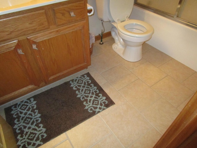 bathroom featuring bath / shower combo with glass door, toilet, vanity, and tile patterned floors