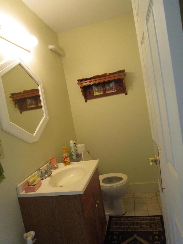 half bathroom with tile patterned floors, baseboards, vanity, and toilet