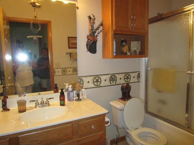 full bathroom with bath / shower combo with glass door, toilet, and vanity