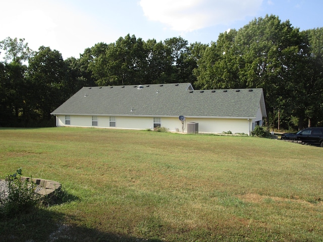 rear view of property with a yard and central AC unit