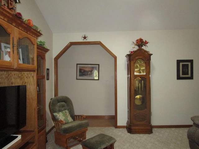 living room featuring carpet floors, lofted ceiling, and baseboards