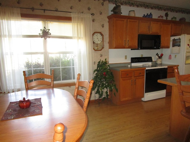 kitchen with black microwave, light wood-style flooring, wallpapered walls, and electric range