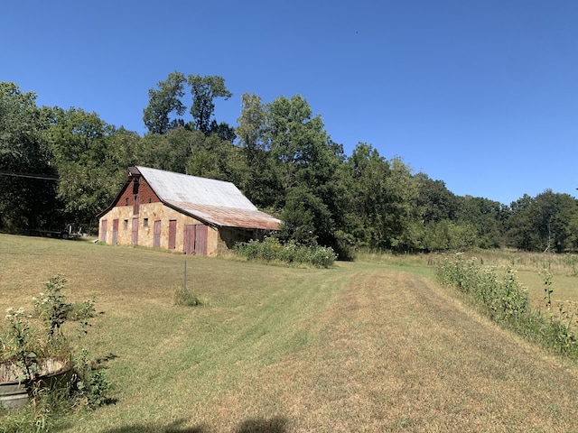 view of yard with a forest view, an outdoor structure, and a barn