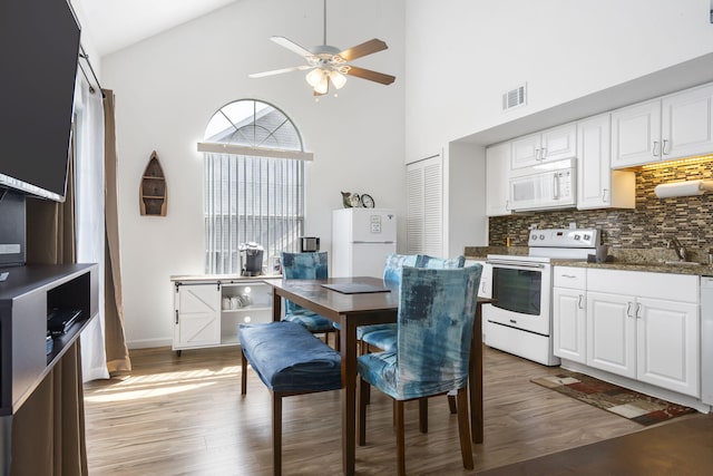 dining area with ceiling fan, light hardwood / wood-style flooring, and high vaulted ceiling