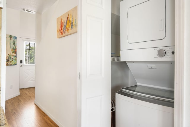 washroom featuring stacked washer and clothes dryer and light hardwood / wood-style floors