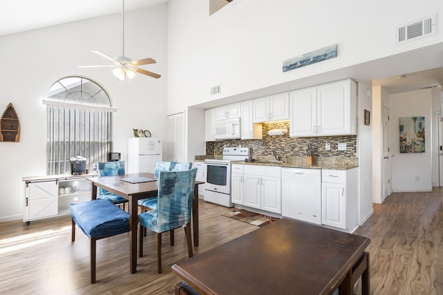 dining space with high vaulted ceiling, ceiling fan, and light hardwood / wood-style floors