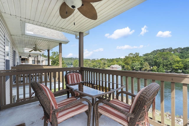 deck with ceiling fan and a water view