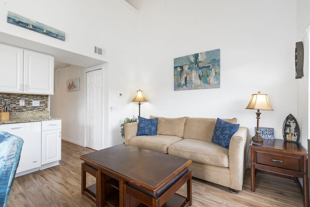 living room with light wood-type flooring and a towering ceiling