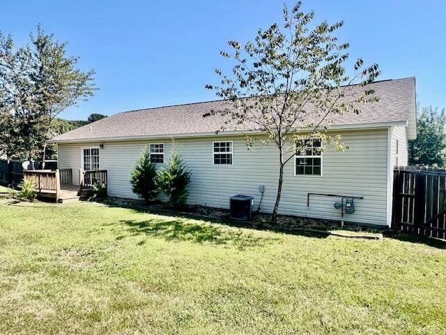 back of house featuring a wooden deck, a yard, and central AC