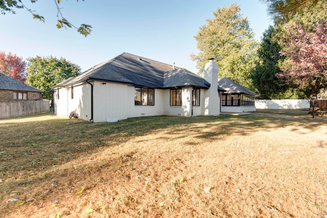 back of property with a sunroom and a lawn