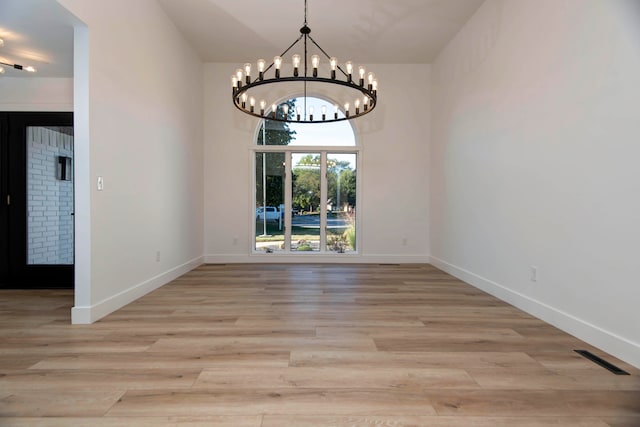 unfurnished dining area featuring light wood-type flooring and a chandelier