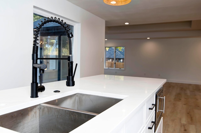 kitchen featuring white cabinets, sink, and light wood-type flooring