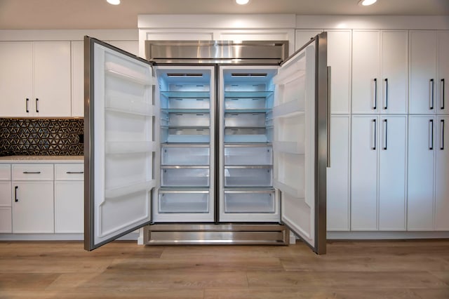 interior space with white cabinetry, backsplash, light wood-type flooring, and built in fridge