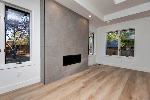 unfurnished living room featuring a tiled fireplace and light hardwood / wood-style flooring