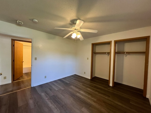 unfurnished bedroom with ceiling fan, dark wood-type flooring, two closets, and a textured ceiling