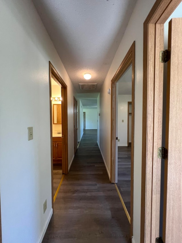 corridor featuring a textured ceiling and dark hardwood / wood-style flooring