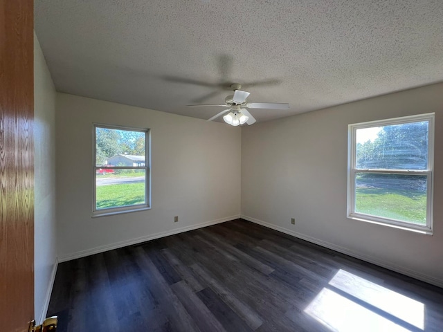 spare room with dark wood-type flooring, plenty of natural light, a textured ceiling, and ceiling fan