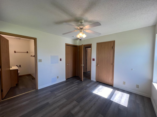 unfurnished bedroom featuring dark wood-type flooring, ensuite bath, a textured ceiling, and ceiling fan