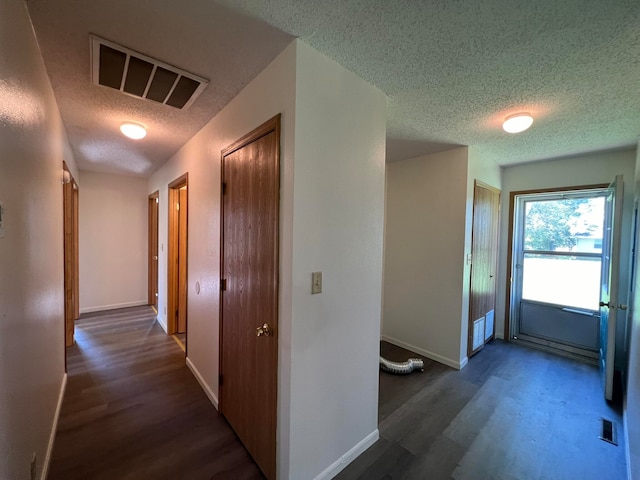 hallway with dark wood-type flooring and a textured ceiling