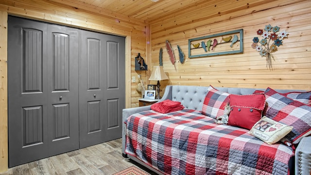 bedroom featuring wood walls, a closet, wood ceiling, and light hardwood / wood-style flooring