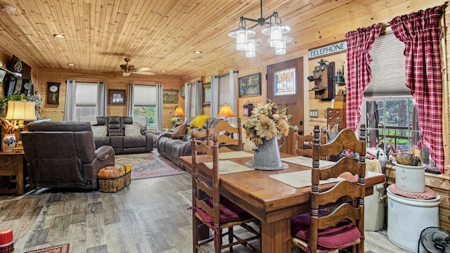 dining area featuring ceiling fan with notable chandelier, wooden walls, hardwood / wood-style floors, and wood ceiling