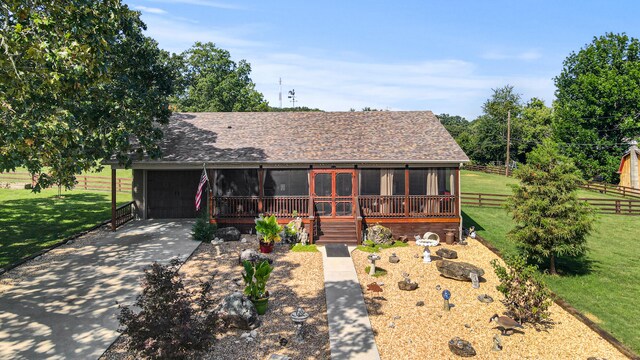 view of front of house featuring a sunroom, a front yard, and a garage