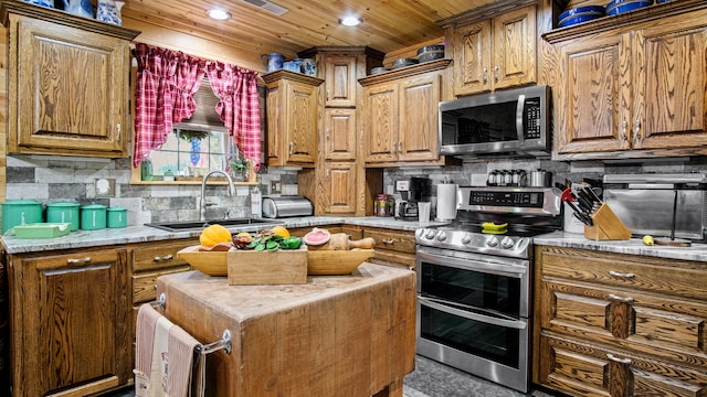 kitchen featuring light stone counters, decorative backsplash, stainless steel appliances, sink, and wooden ceiling