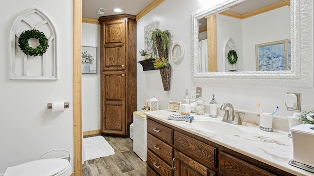 bathroom featuring vanity, crown molding, hardwood / wood-style floors, and toilet