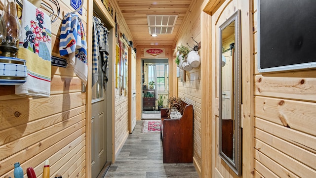 hallway featuring a barn door, wood walls, wood ceiling, and dark hardwood / wood-style floors