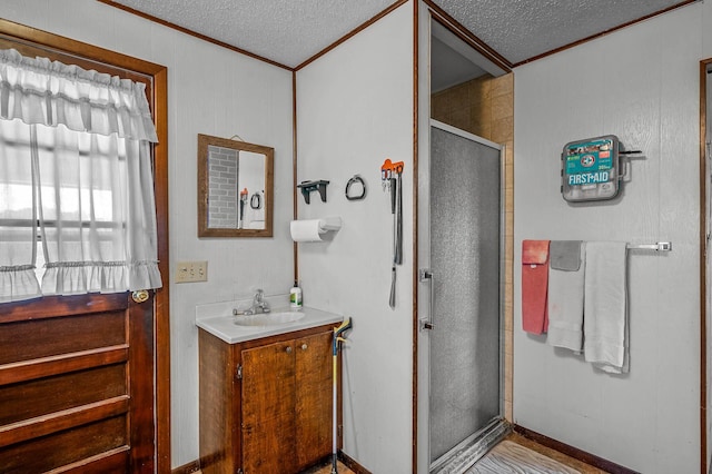 bathroom with an enclosed shower, crown molding, vanity, and a textured ceiling