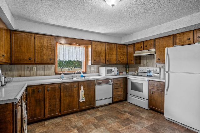 kitchen featuring a raised ceiling, white appliances, sink, and a textured ceiling