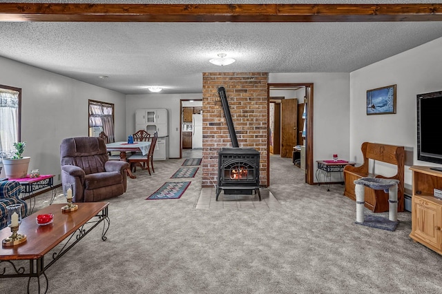 living room with a textured ceiling, a wood stove, and carpet