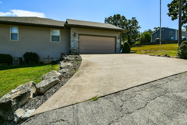 view of front of property with a front yard, a garage, and cooling unit