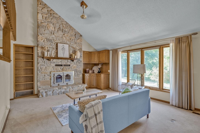 carpeted living room with ceiling fan, a stone fireplace, a textured ceiling, and high vaulted ceiling