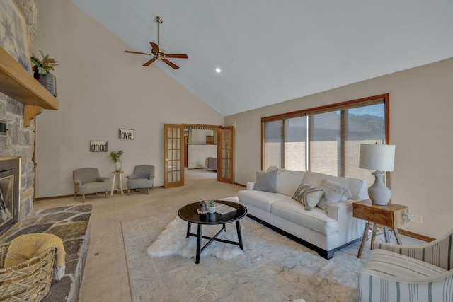 living room featuring ceiling fan, french doors, a stone fireplace, high vaulted ceiling, and light carpet