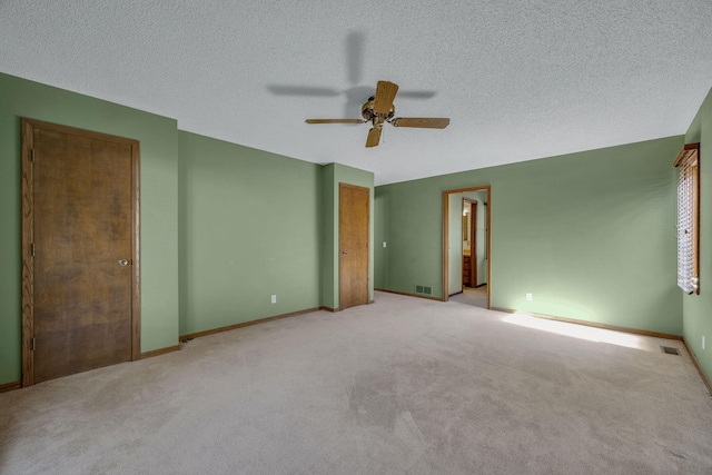 empty room with light carpet, ceiling fan, and a textured ceiling