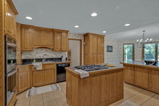 kitchen featuring appliances with stainless steel finishes, sink, decorative light fixtures, an inviting chandelier, and a kitchen island