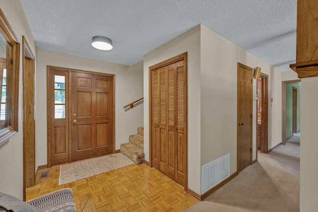 entryway featuring light parquet flooring and a textured ceiling