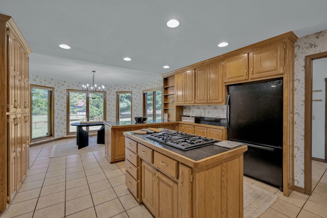 kitchen featuring a center island, decorative light fixtures, black fridge, and stainless steel gas stovetop