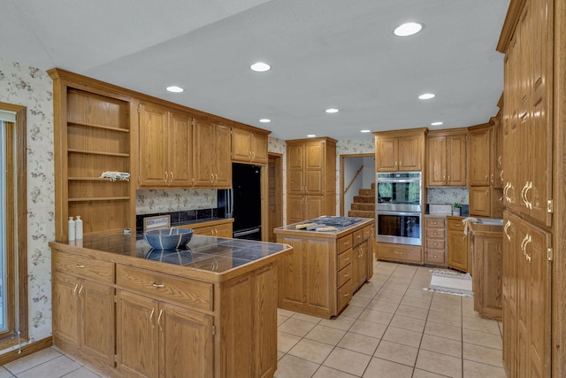 kitchen featuring a textured ceiling, stainless steel appliances, tile countertops, a center island, and light tile patterned flooring