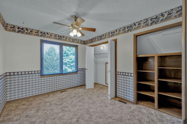 unfurnished bedroom featuring ceiling fan, carpet floors, and a textured ceiling