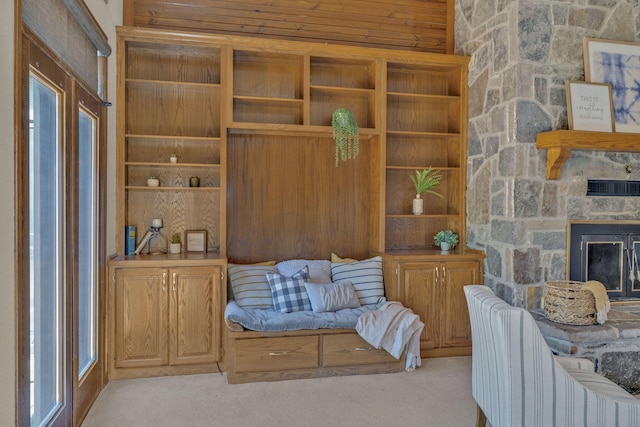 sitting room featuring a stone fireplace and light carpet