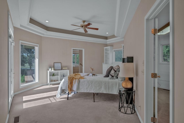 carpeted bedroom featuring a tray ceiling, ceiling fan, and crown molding