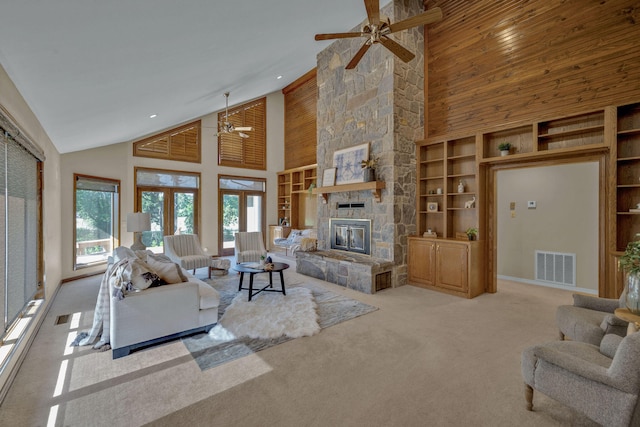 carpeted living room featuring high vaulted ceiling, french doors, a stone fireplace, built in shelves, and ceiling fan