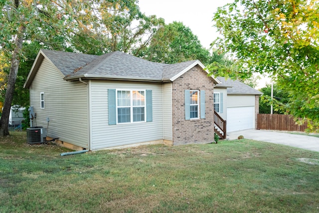 view of front of property with a garage, a front yard, and central AC unit