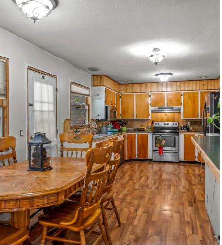 kitchen with light wood-style floors, brown cabinetry, appliances with stainless steel finishes, and under cabinet range hood