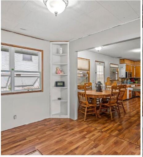 dining room with plenty of natural light, built in features, and light wood-style floors