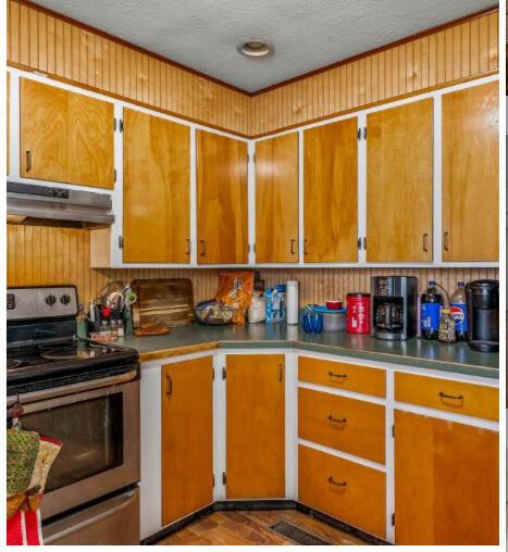 kitchen with stainless steel range with electric cooktop, under cabinet range hood, and a textured ceiling