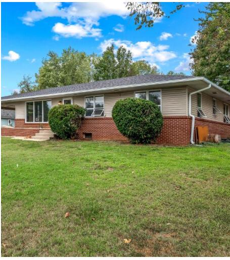 ranch-style house featuring a front lawn and brick siding