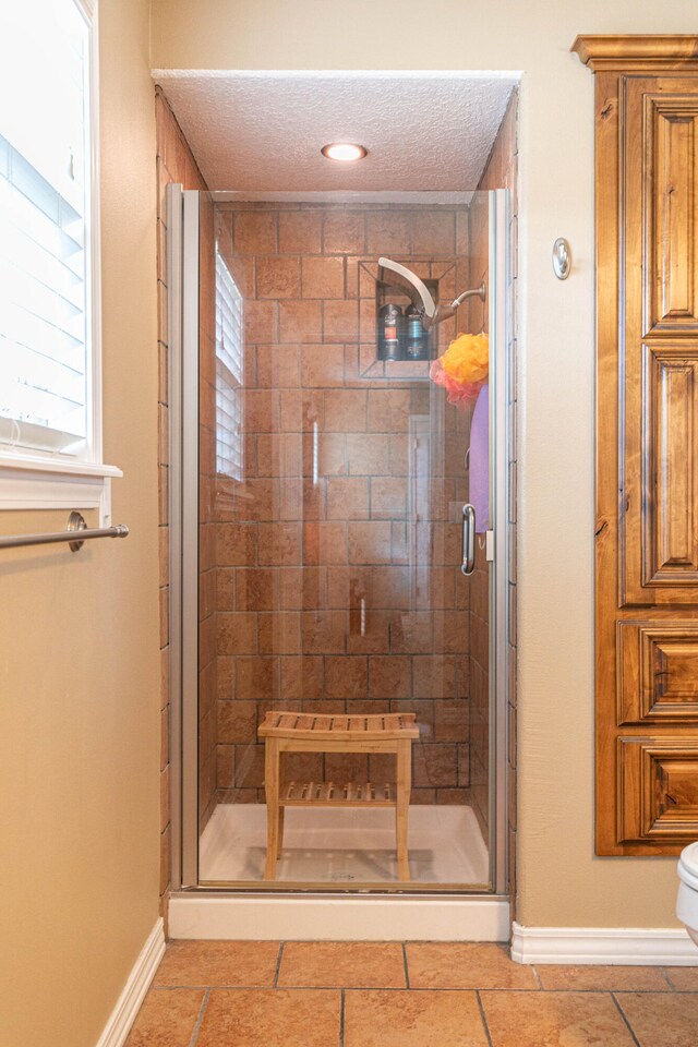 bathroom with tile patterned flooring, an enclosed shower, toilet, and a textured ceiling